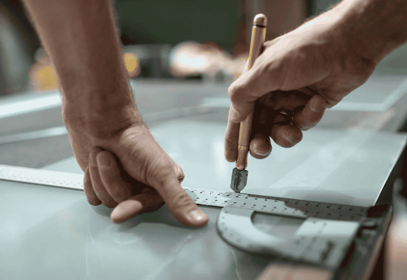 un vitrier taille le verre à la bonne taille pour un remplacement de fenêtre à Mauléon Licharre